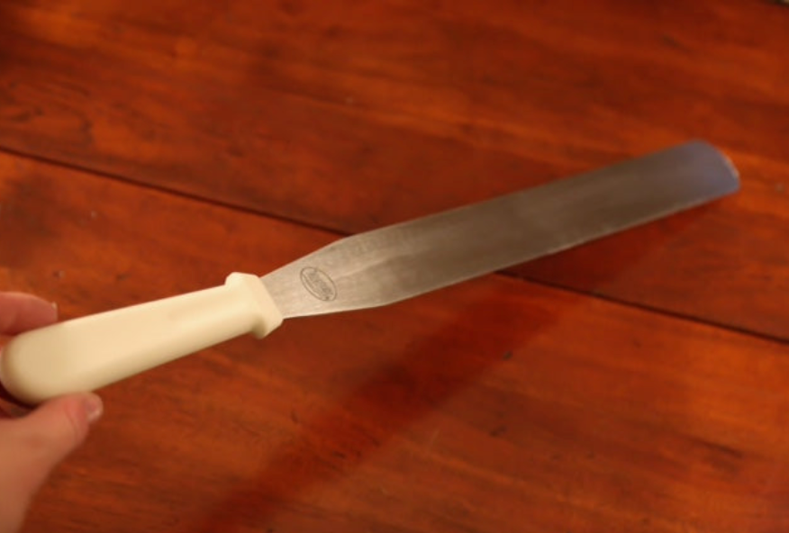Knife with a white handle held over a wooden surface